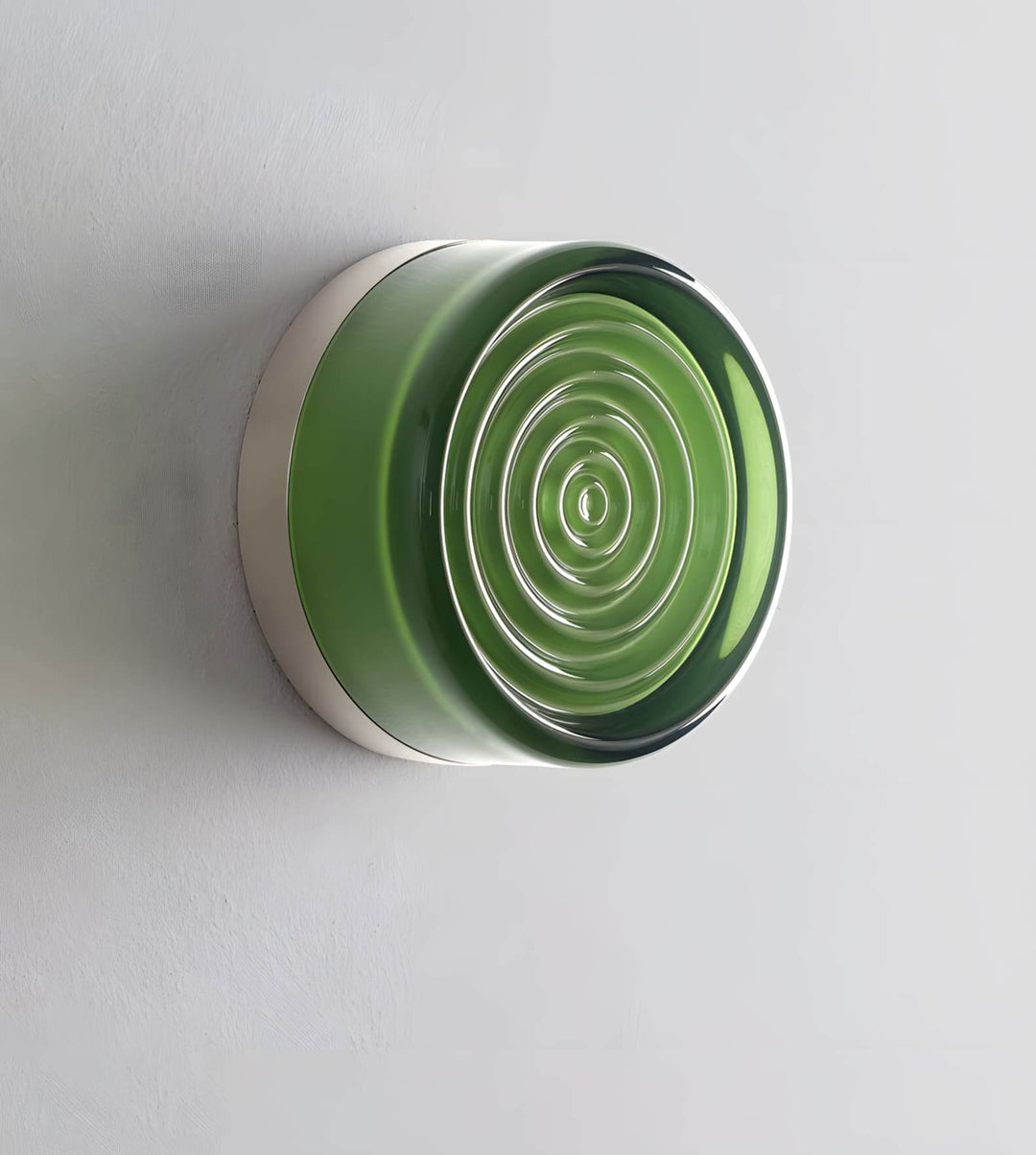 Unlit green glass wall sconce detail showing concentric rings and metal edge.