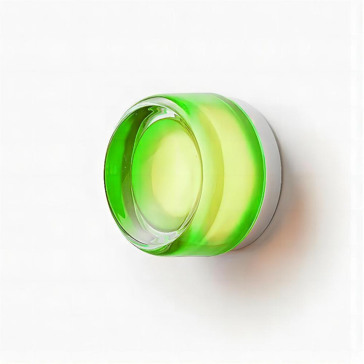 Green glass wall sconce lit on a white background with a warm center glow.