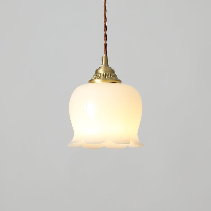 Illuminated resin pendant light with a bell-shaped floral shade, brass cap, and twisted fabric cord