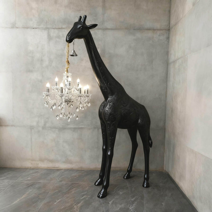 Large black and silver giraffe floor lamp holding an illuminated crystal fixture