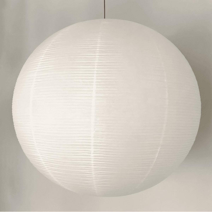 Large white round paper lantern pendant shown close up with a black wire