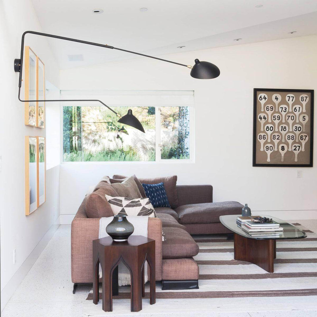 Large black two-light swing arm wall lamp extending over a modern living room sectional