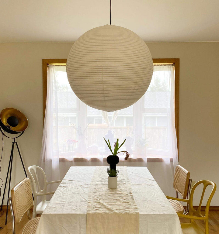 Large white paper lantern pendant suspended over a bright dining area