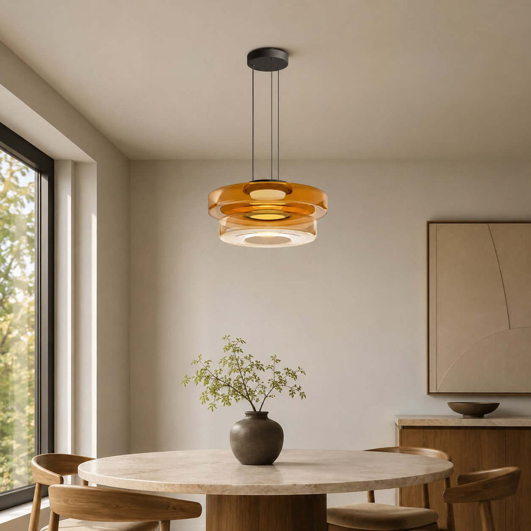 Orange two-layer glass pendant light casting warm light over a round dining table