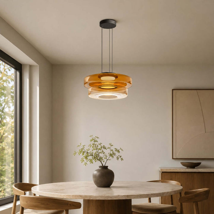 Orange two-layer glass pendant light casting warm light over a round dining table