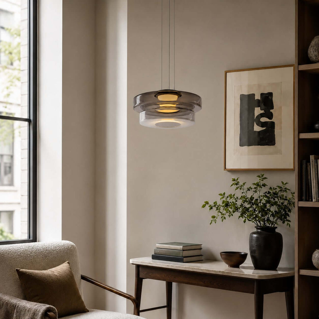 Smoke Grey two-layer glass pendant light illuminating a warm living room reading corner