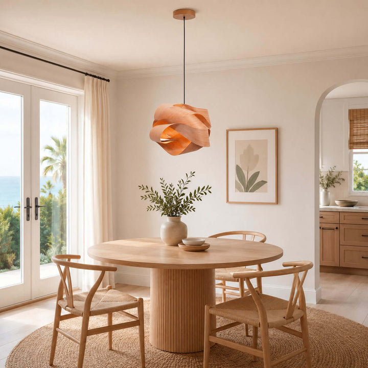Link pendant light above a round dining table in a bright coastal-style interior