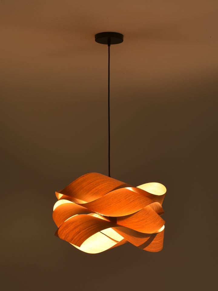 Glowing Link wood pendant light suspended against a dark warm-toned background
