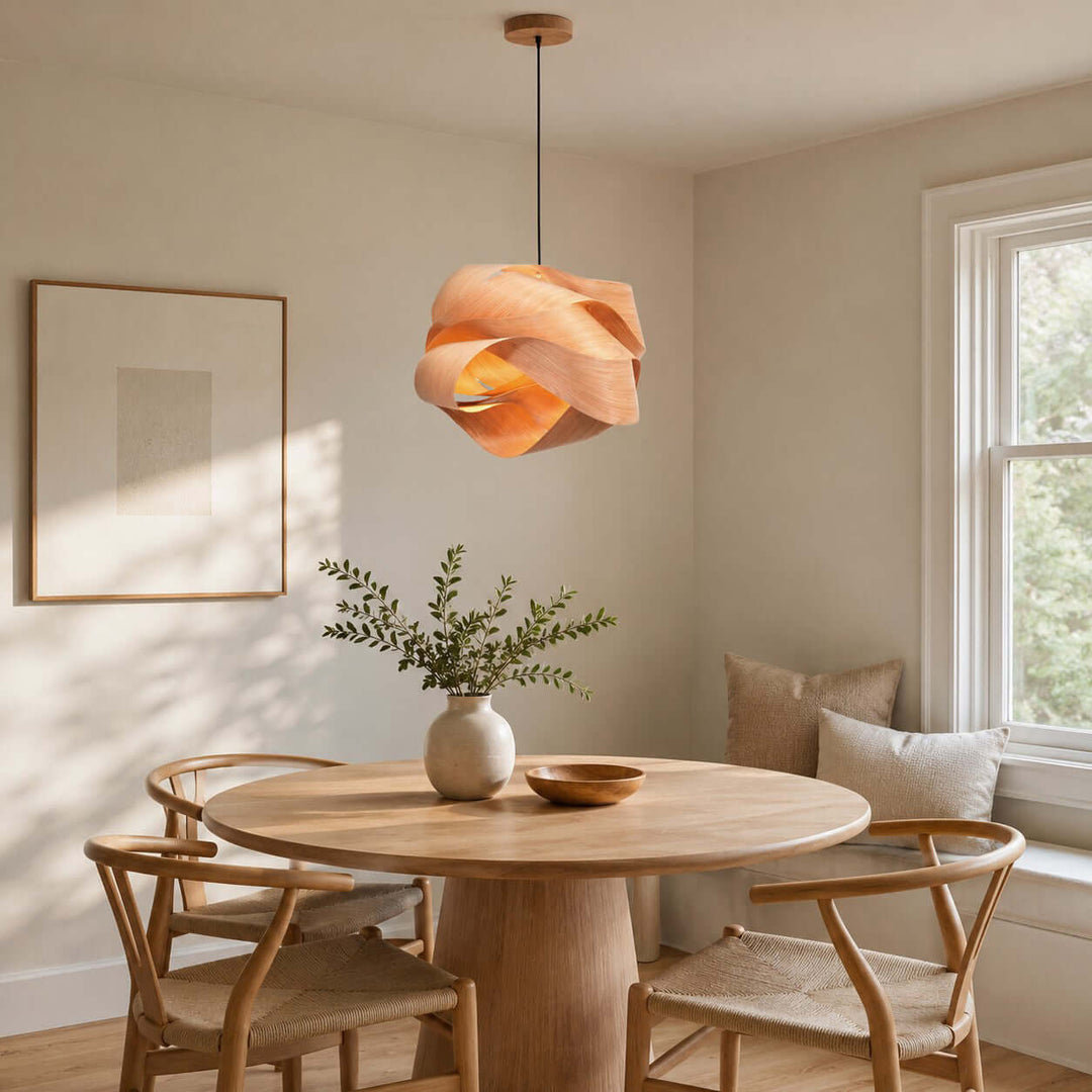 Link pendant light over a round wood table in a sunlit neutral dining room