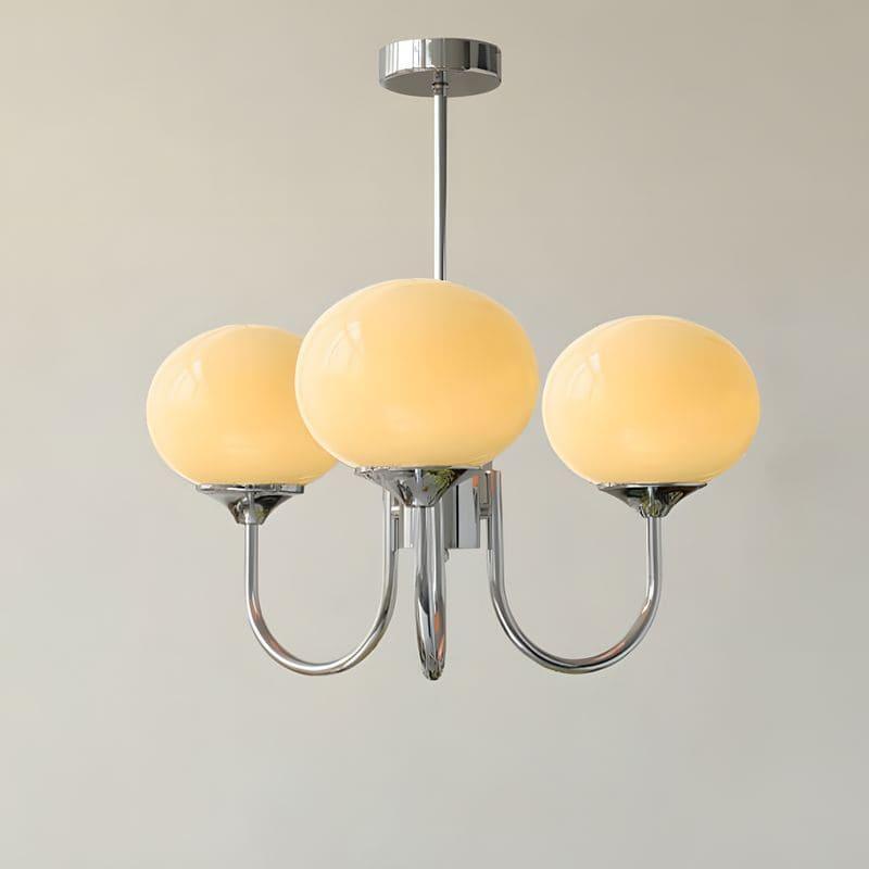 Illuminated three-light chandelier with a chrome frame and warm cream glass globes.