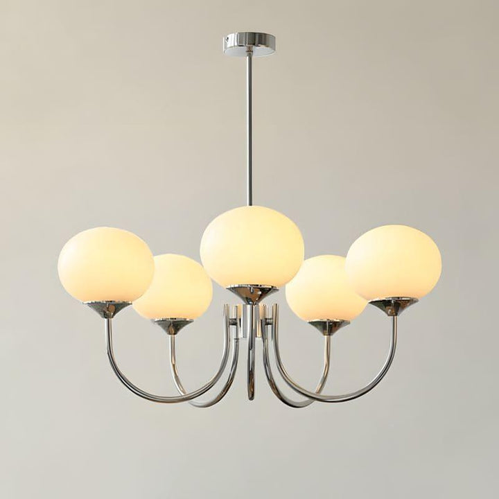 Illuminated five-light chandelier with a chrome frame and warm cream glass globes.