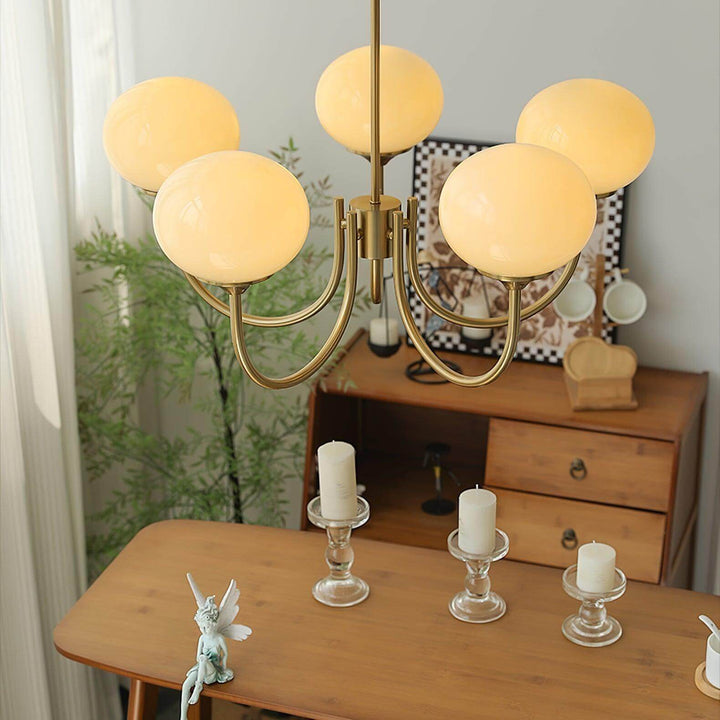 Close-up of five illuminated cream glass globes and the curved copper chandelier frame.
