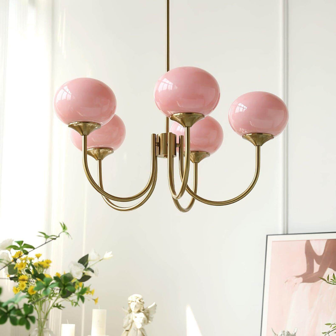 Close-up of the five-light Marshmallow chandelier with pink glass globes and curved copper arms.
