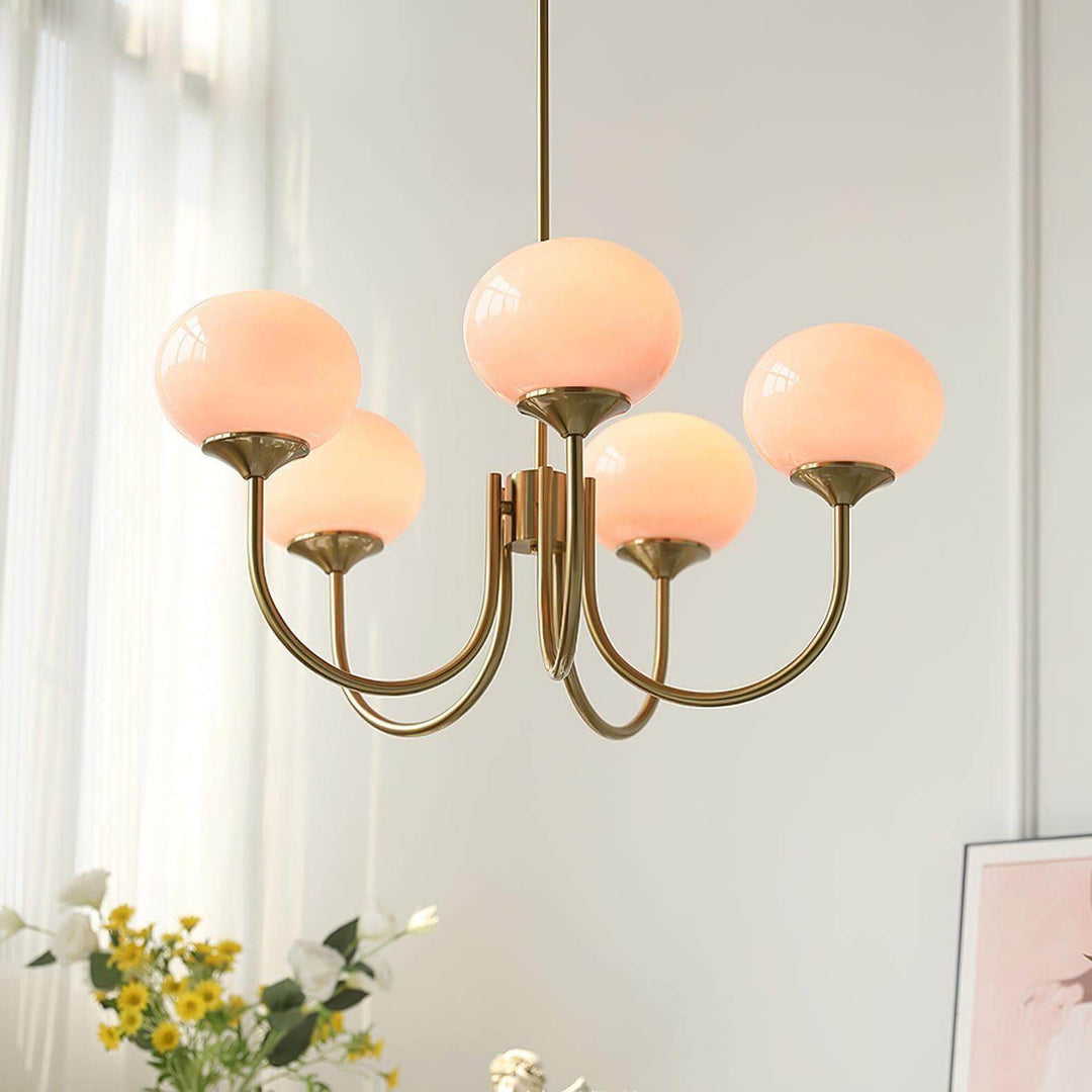 Illuminated pink glass globes on the five-light Marshmallow chandelier with a copper frame.
