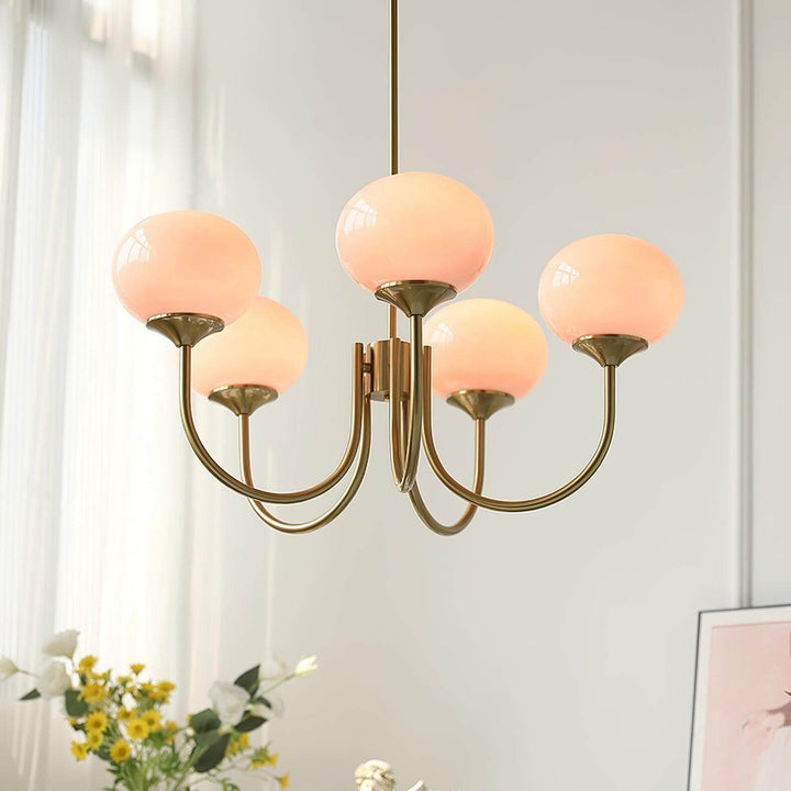 Illuminated pink glass globes on the five-light Marshmallow chandelier with a copper frame.
