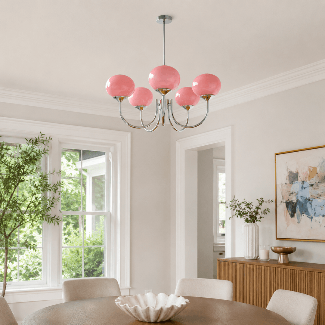Five-light pink glass chandelier with a chrome frame in a bright modern dining room.
