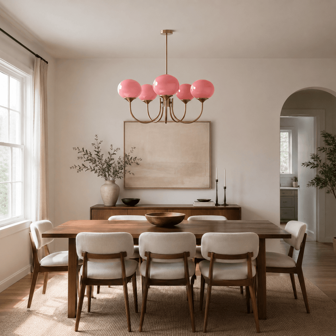 Five-light pink glass Marshmallow chandelier above a long wood dining table.
