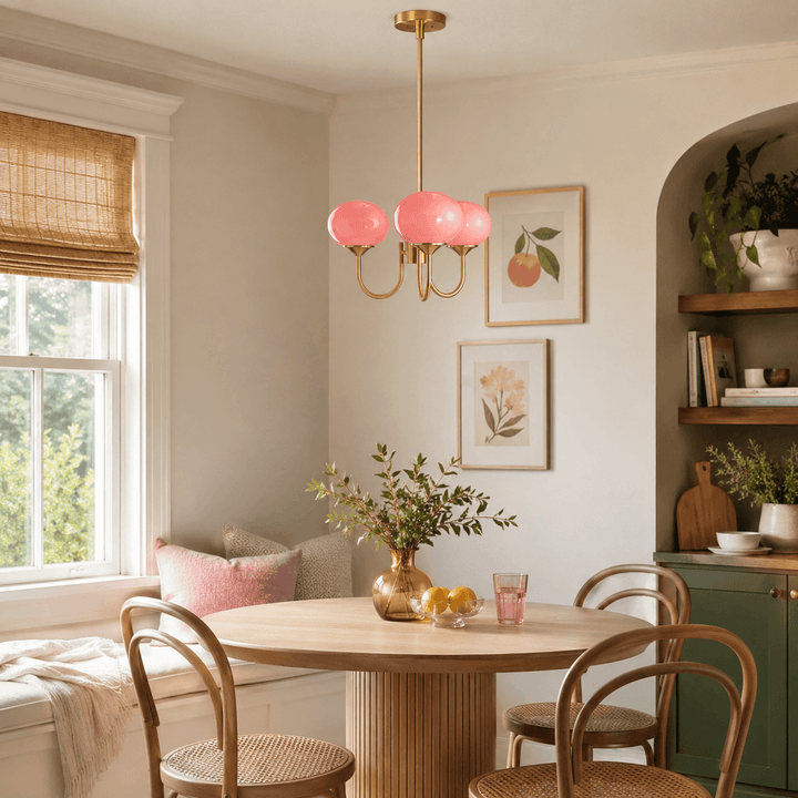 Pink glass Marshmallow chandelier above a round wood table in a sunlit dining nook.
