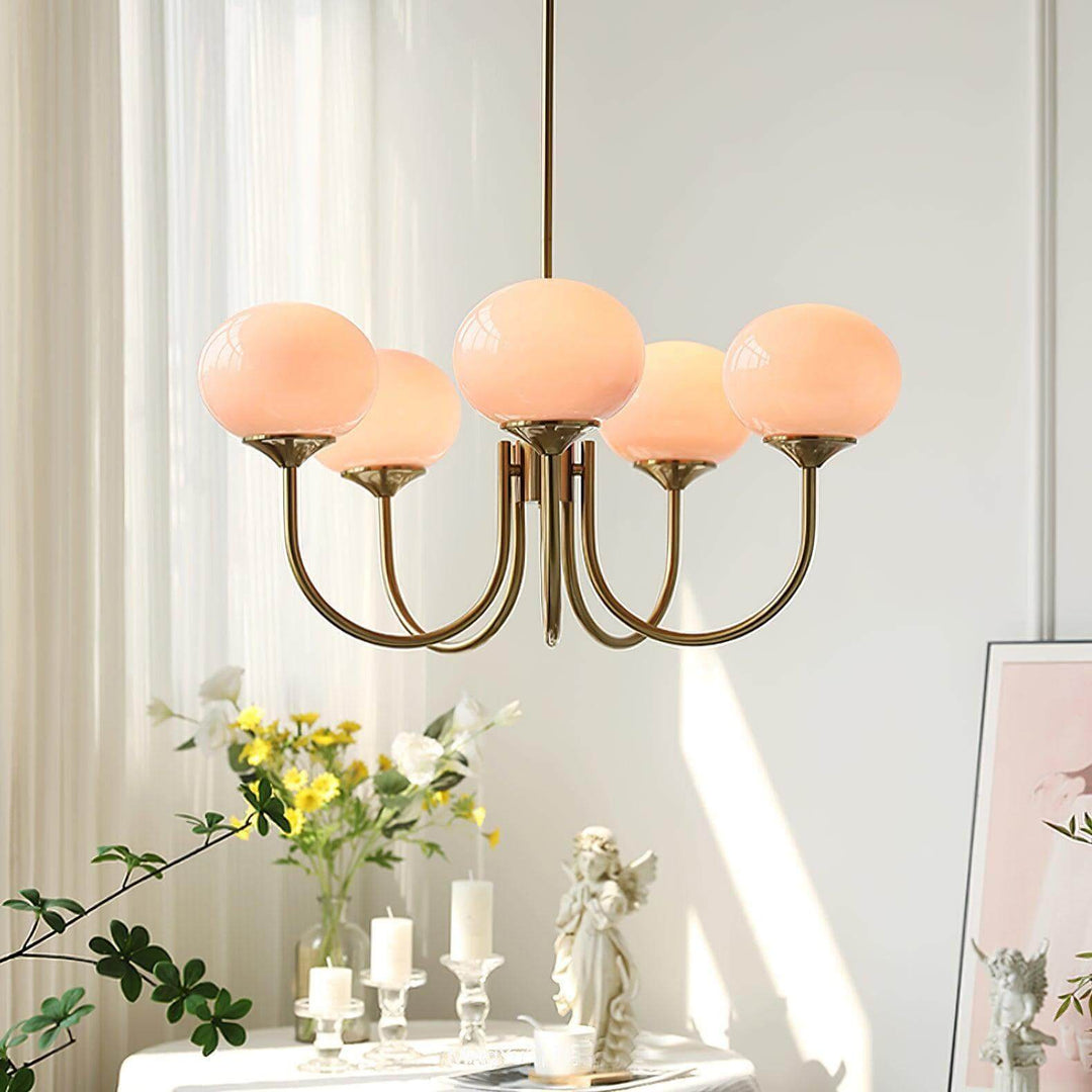 Lower-angle view of the illuminated pink glass chandelier and curved metal arms.
