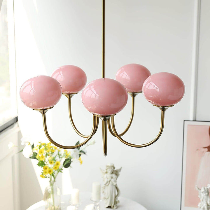 Front view of the Marshmallow chandelier with five pink glass globes and a copper finish.
