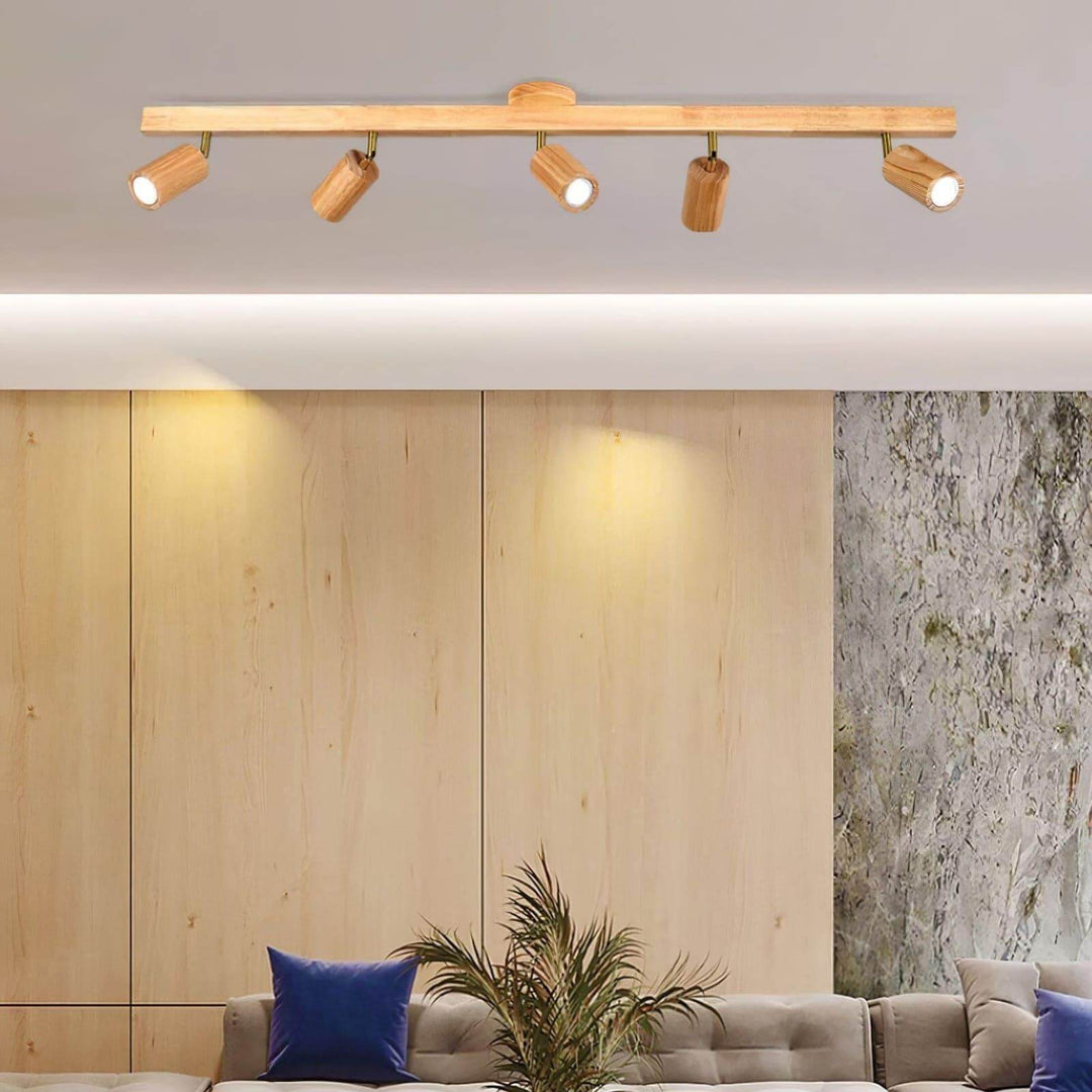 Front view of five-head Merlo natural wood track lighting casting focused light across a modern living room