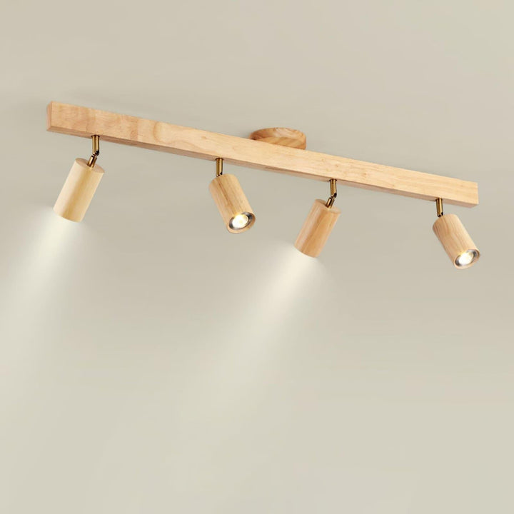 Four-head Merlo natural wood track lighting with adjustable spotlights illuminated against a light ceiling