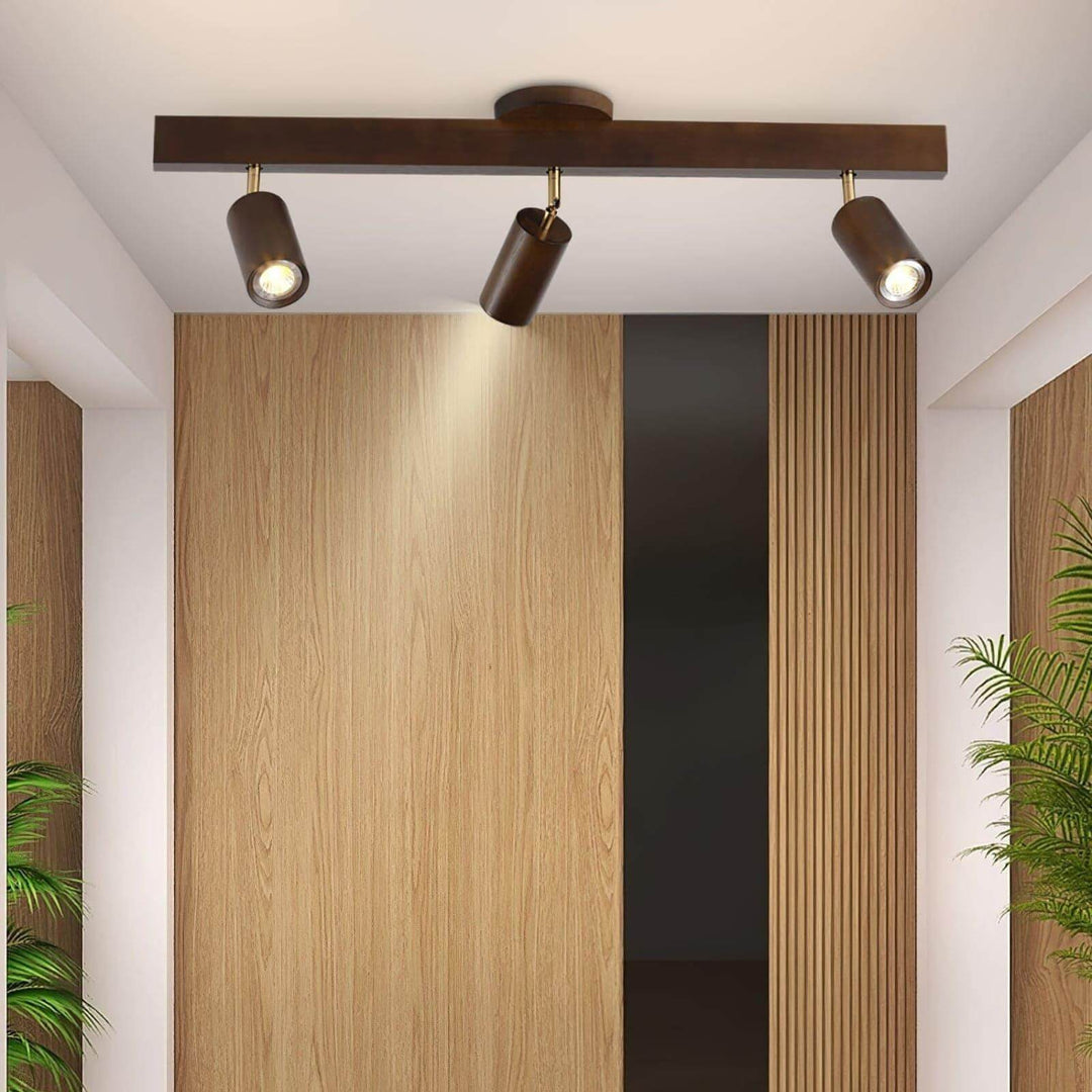 Three-head Merlo walnut track lighting mounted above a modern interior with natural wood wall panels