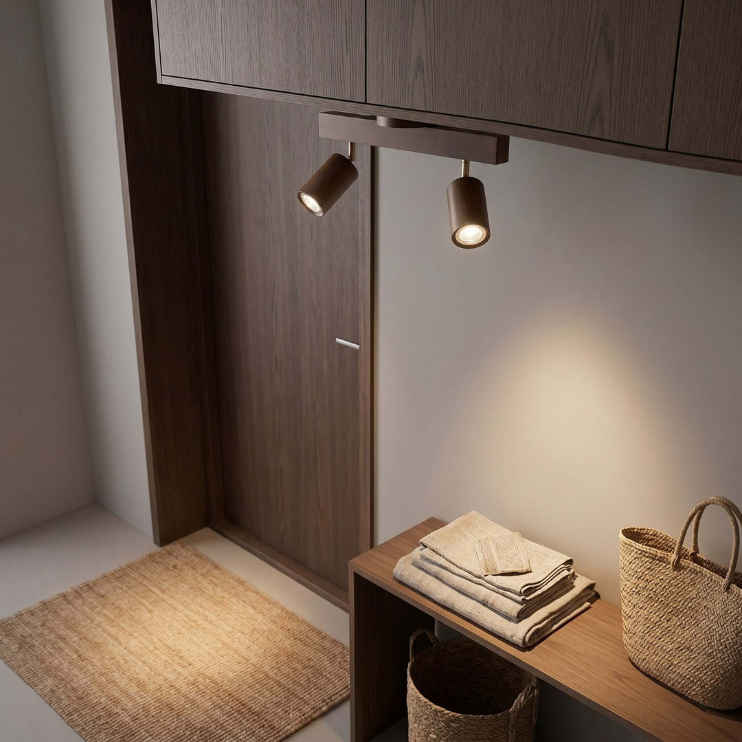 Two-head Merlo walnut wood track lighting providing focused light in an entryway storage area with woven baskets
