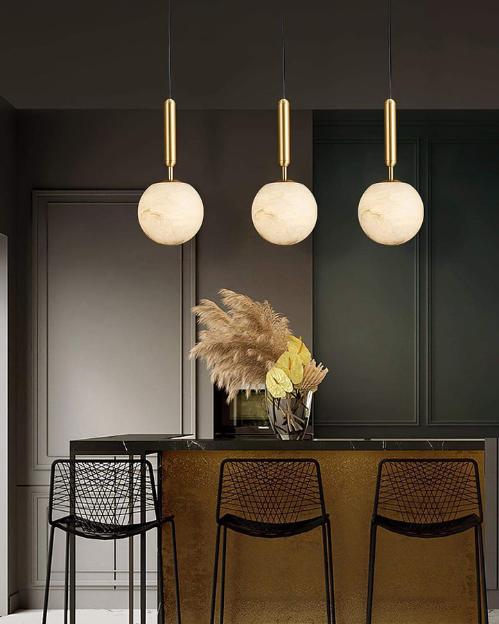 Modern brass and alabaster kitchen island pendant lights in a dark contemporary interior