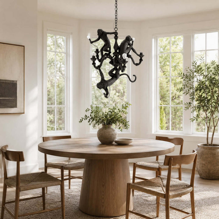 Black Monkey Chandelier above a round wood dining table in a bright dining room