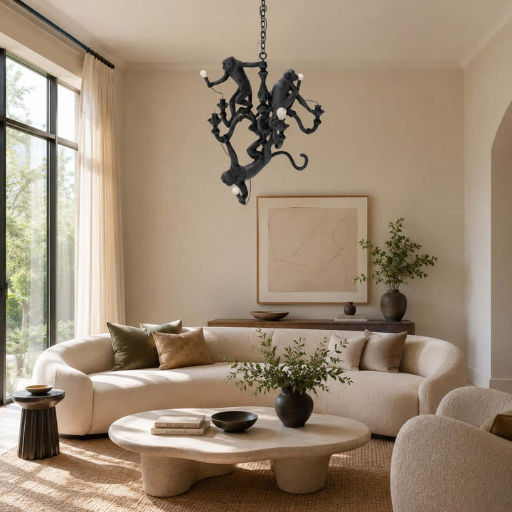 Black sculptural monkey chandelier in a sunlit living room with a curved cream sofa