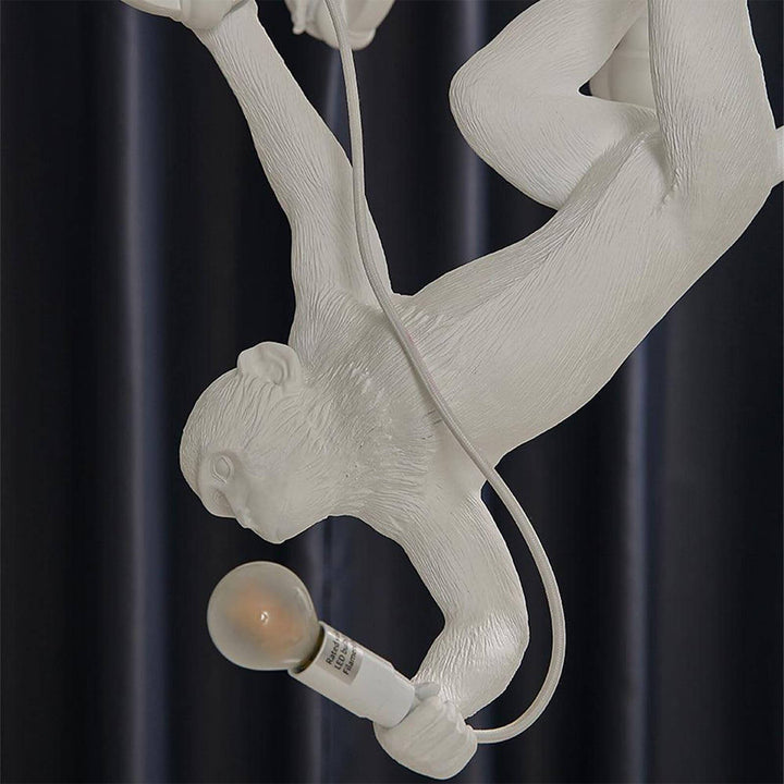 Close-up of the hanging white monkey holding a globe bulb and electrical cord