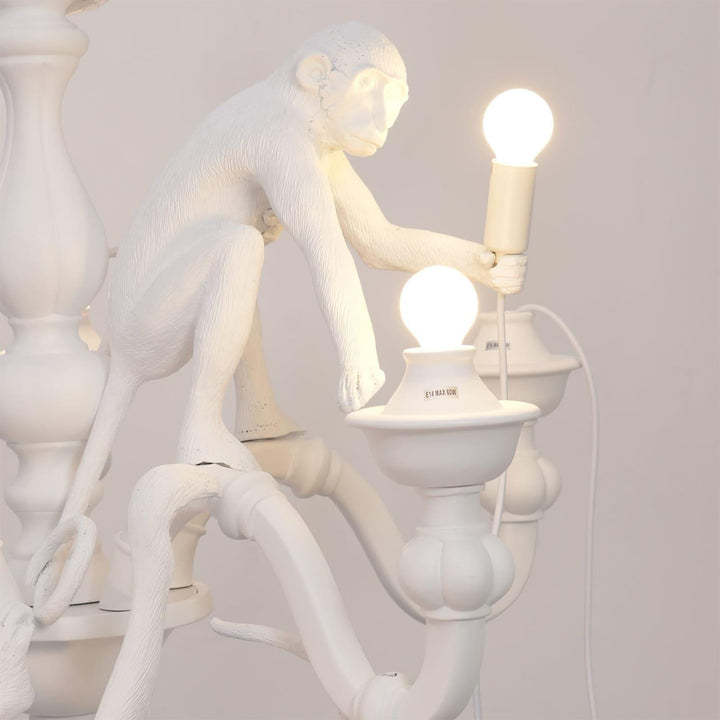 Close-up of a white sculpted monkey holding a glowing bulb on the chandelier