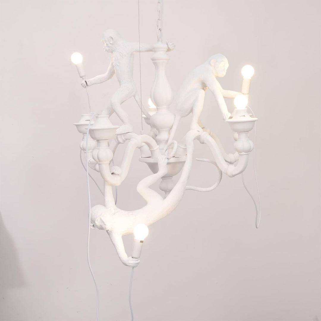 Front view of the illuminated white Monkey Chandelier against a soft pale wall