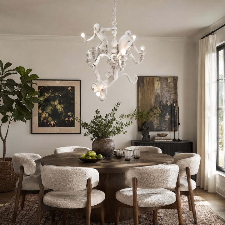 White Monkey Chandelier above a round dark wood dining table in a bright art-filled room