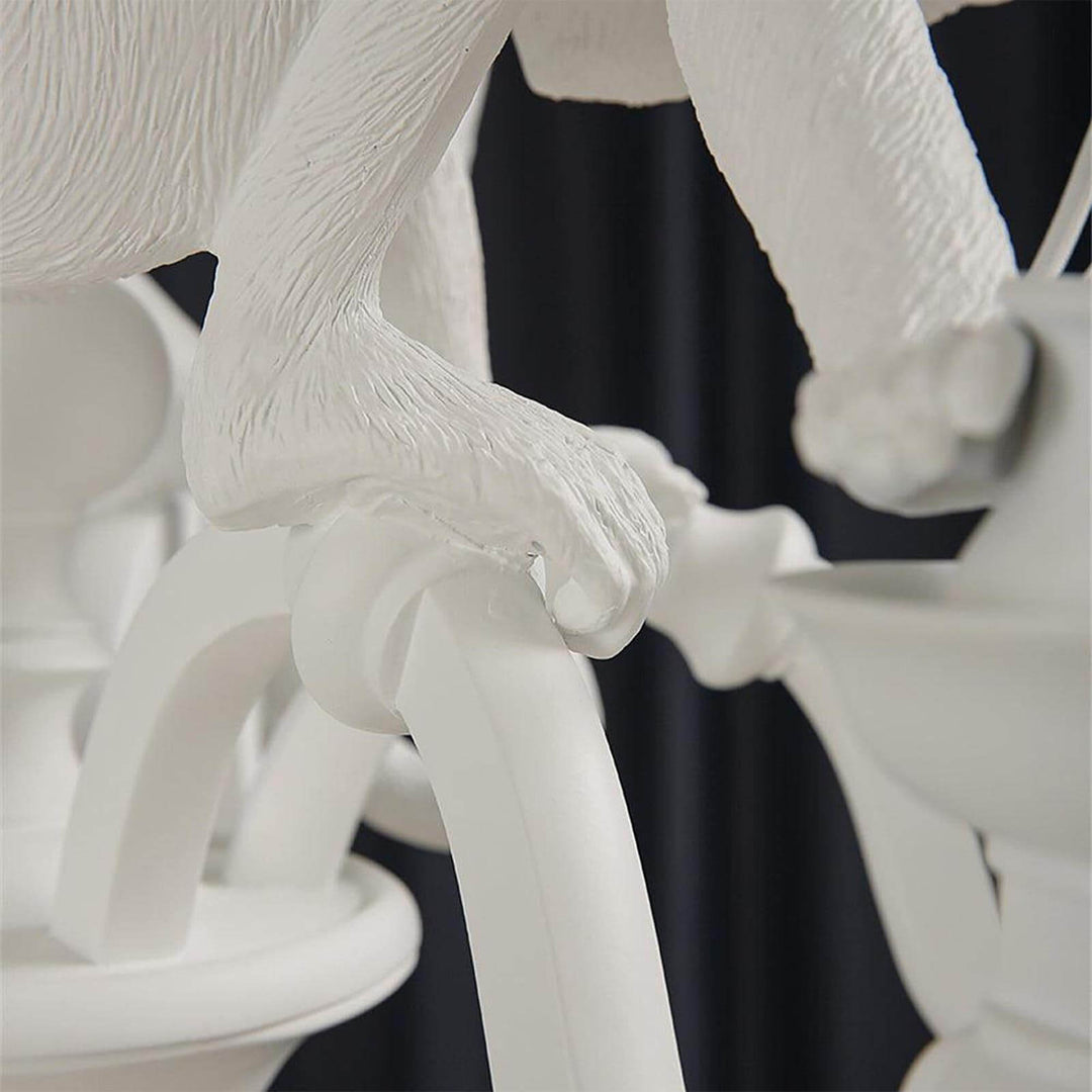 Macro detail of a sculpted white monkey hand gripping the curved chandelier arm
