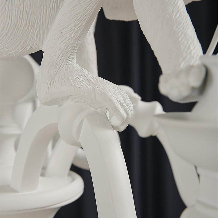 Macro detail of a sculpted white monkey hand gripping the curved chandelier arm