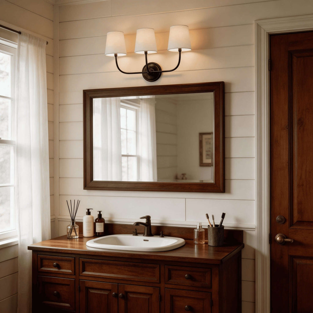 Black three-light Multi Wall Sconce above a wood-framed bathroom vanity mirror