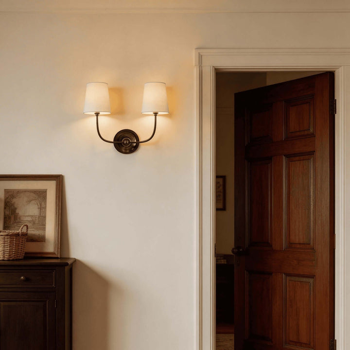 Black two-light Multi Wall Sconce glowing beside a dark wood doorway