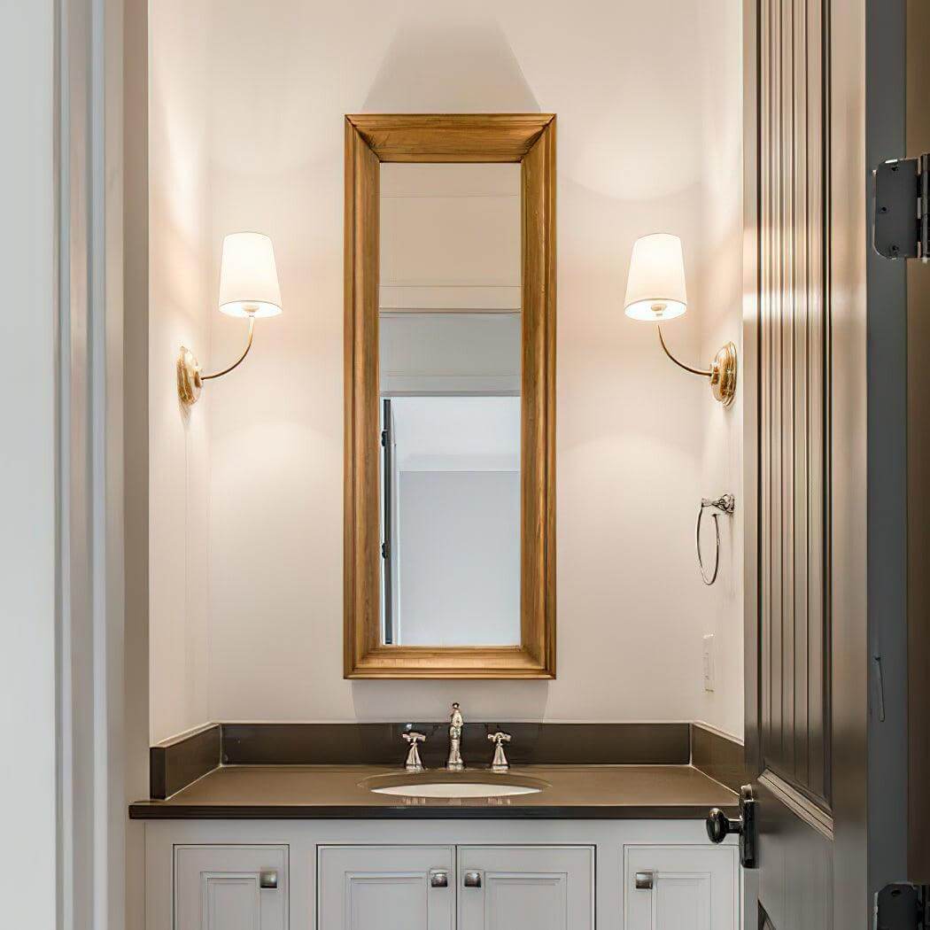 Pair of brass single-light wall sconces flanking a narrow bathroom mirror