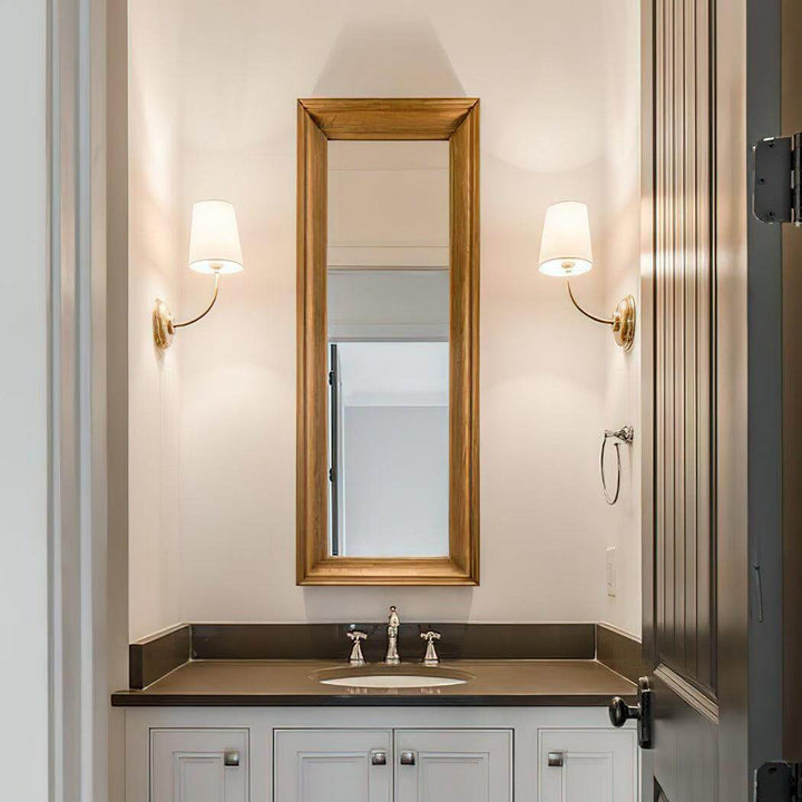 Pair of brass single-light wall sconces flanking a narrow bathroom mirror