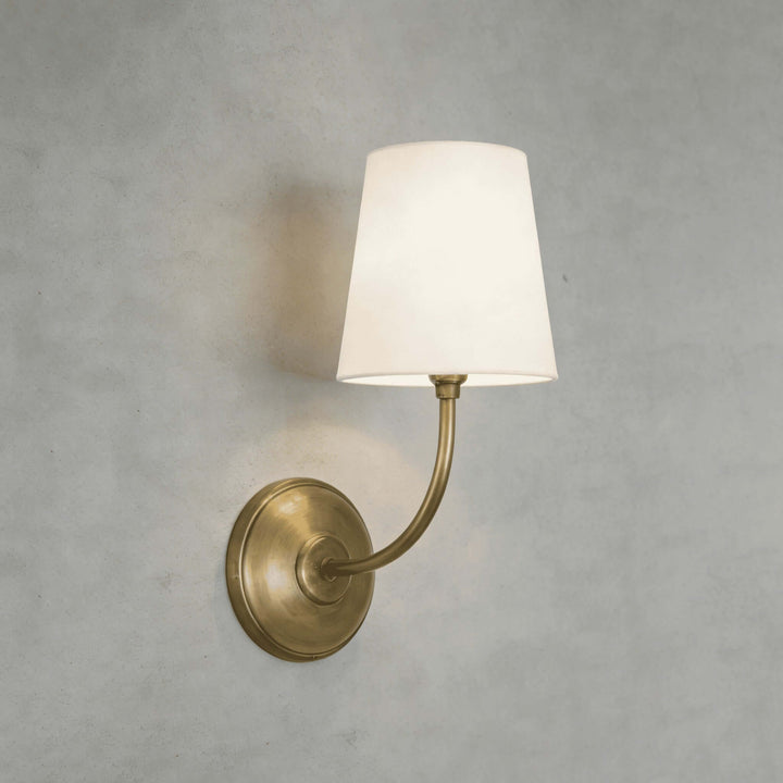 Close-up of the brass Multi Wall Sconce with a glowing white fabric shade