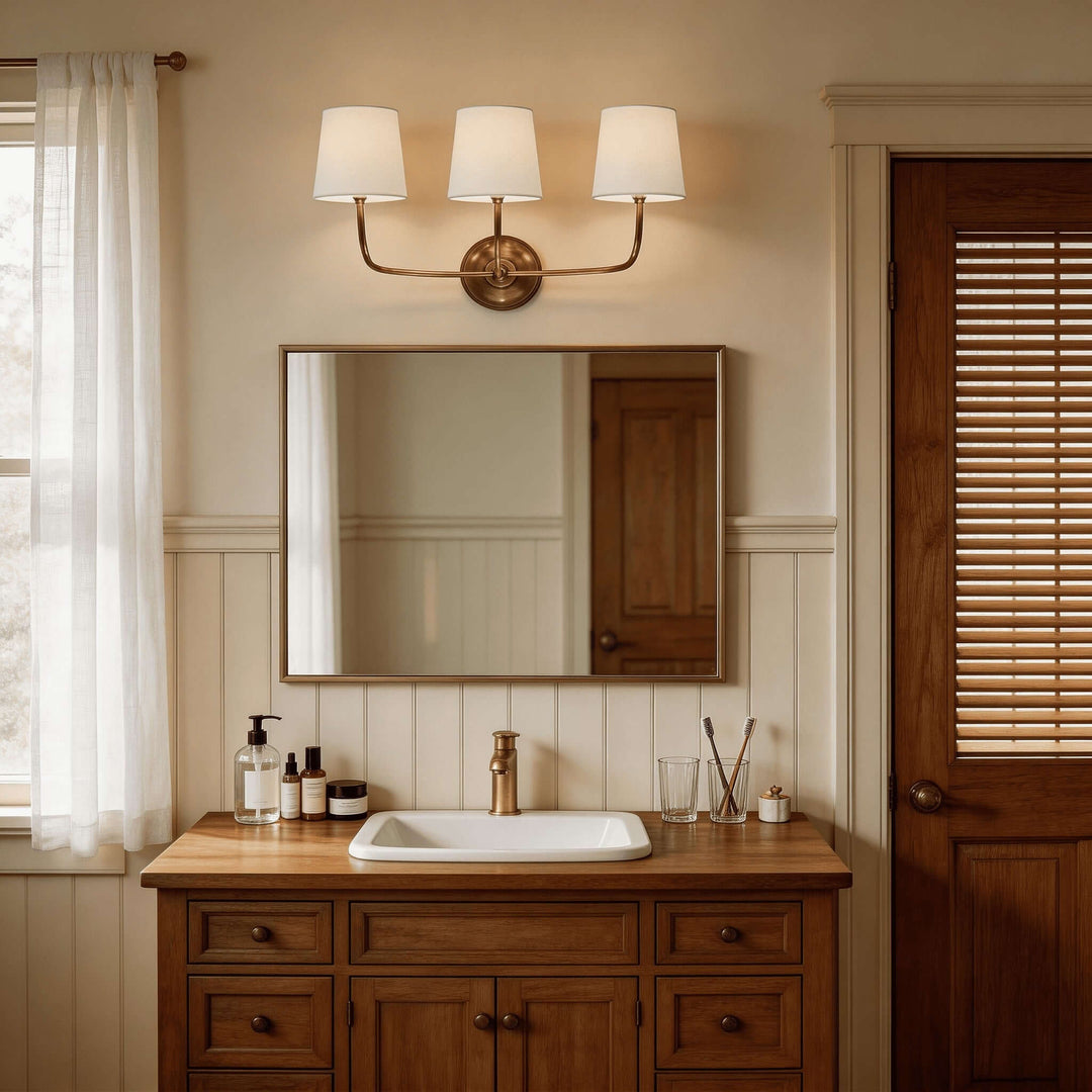 Brass three-light Multi Wall Sconce above a mirror and wood bathroom vanity