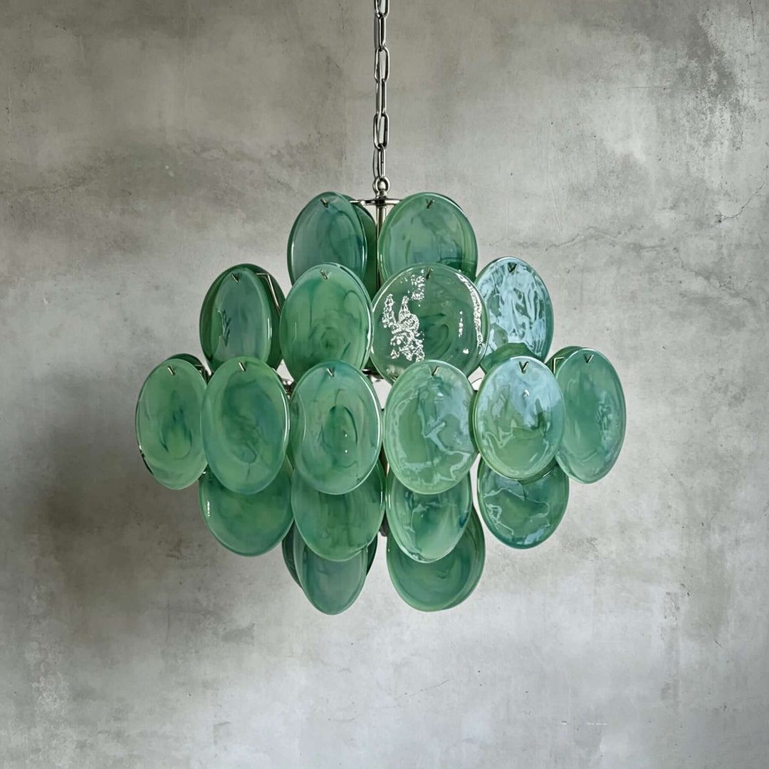 Green Murano Disk Chandelier with layered handcrafted glass discs against a gray concrete wall