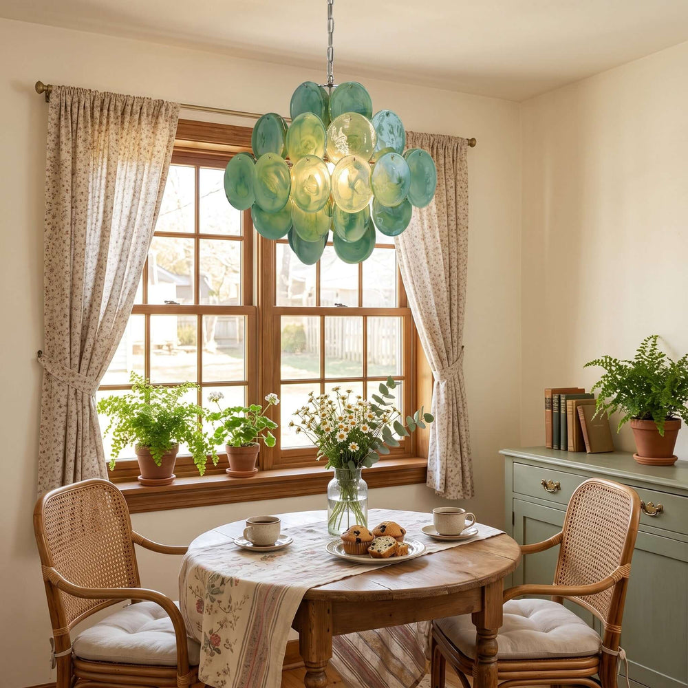 Green Murano glass dining room chandelier above a round wood table in a sunlit breakfast nook