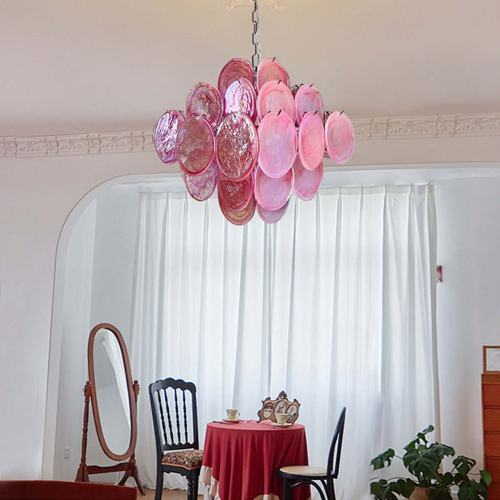 Pink Murano Disk Chandelier above a small red table in a room with white curtains and vintage decor