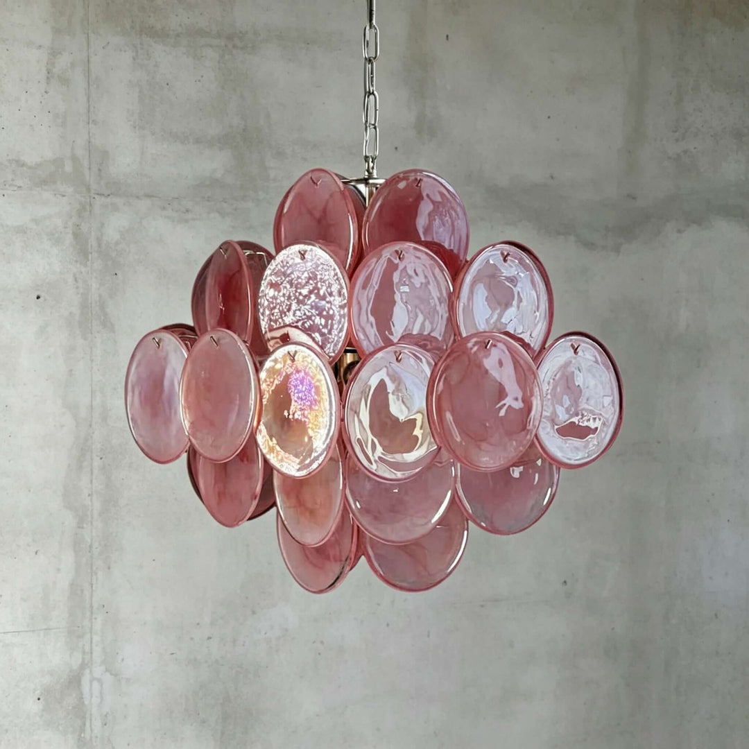 Pink Murano Disk Chandelier with reflective textured glass discs against a gray concrete wall