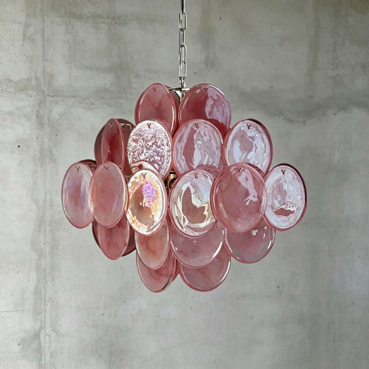 Pink Murano Disk Chandelier with reflective textured glass discs against a gray concrete wall