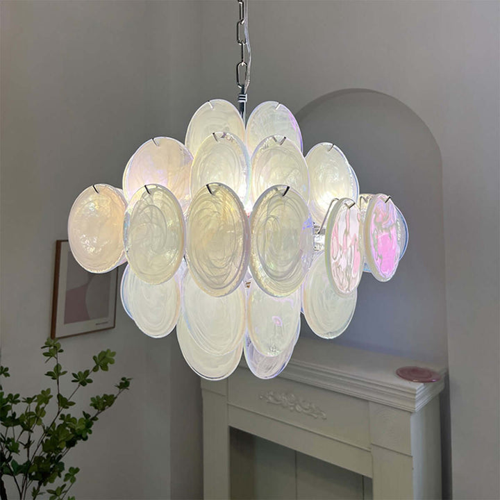 Close-up of a glowing white Murano glass chandelier beside a decorative white fireplace