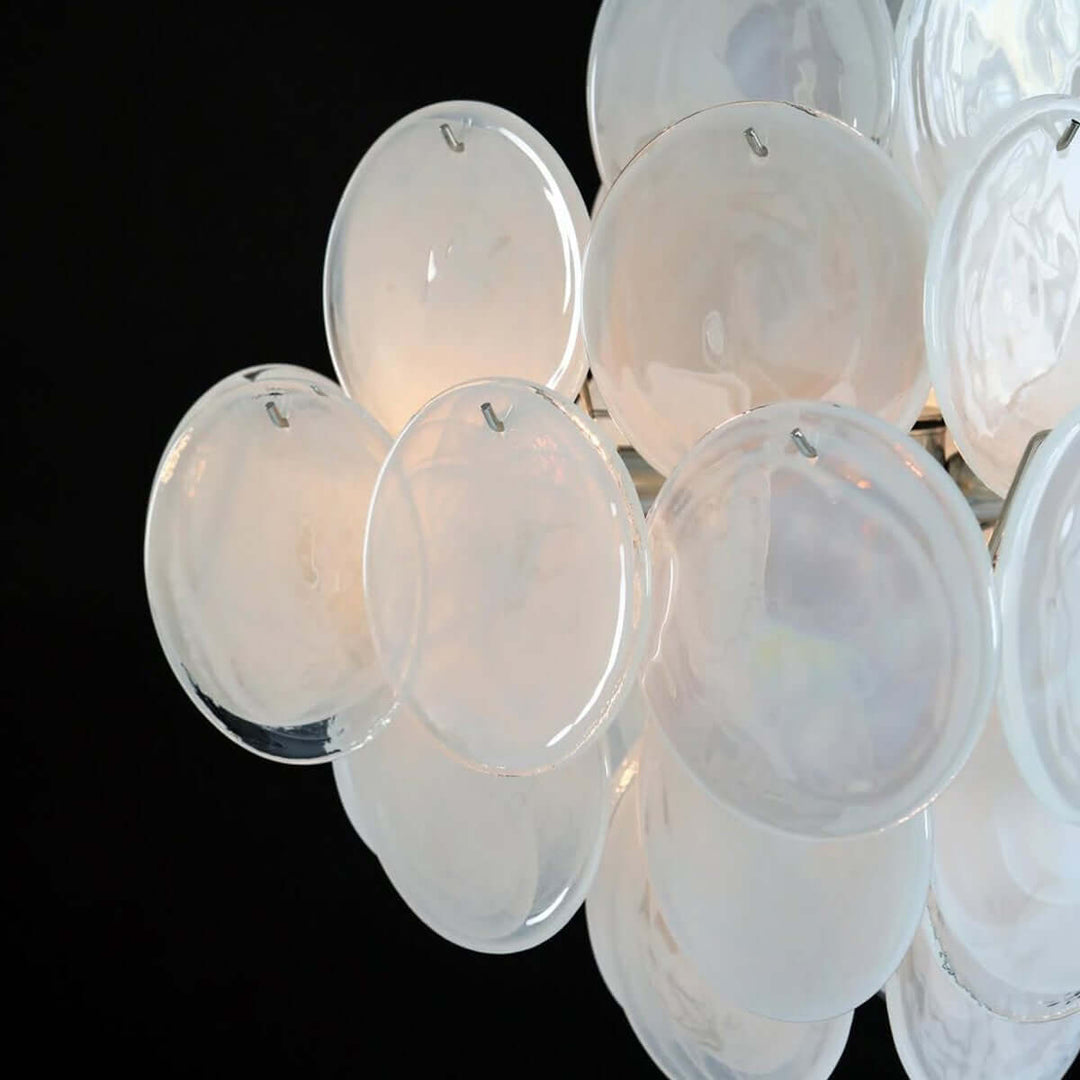 Close-up of layered white Murano glass discs with iridescent surfaces and small metal mounting hooks